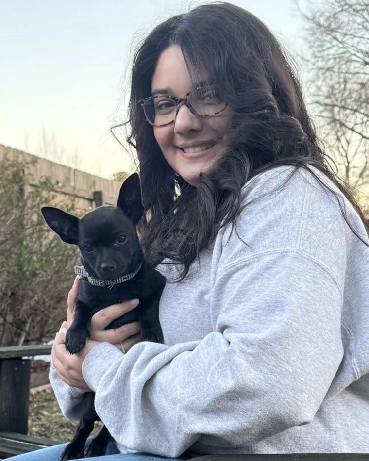 Lana Garcia, graphic designer and branding specialist, holding a small black dog